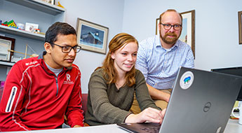 Professor with students on laptop