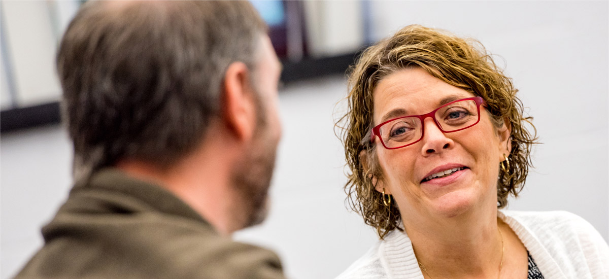 Professor Caroline Carvill smiles while talking with a colleague at a faculty summer seminar. 