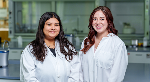 Female students wearing lab coats. 