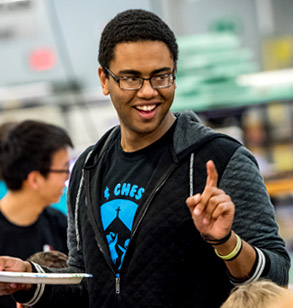 Smiling male student holding up finger to indicate the number one.