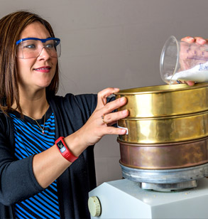 Dr. Henthorn pour a substance from a beaker to a metal container.