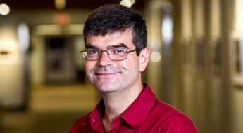 !A smiling Dr. Allen Holder standing in a hallway at Rose-Hulman