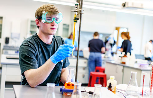 A male student  works on an experiment in a chemistry lab.