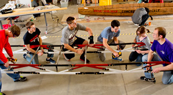 Group of students gather around building materials.