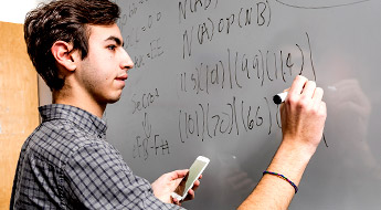 Student does math problem on a white board.