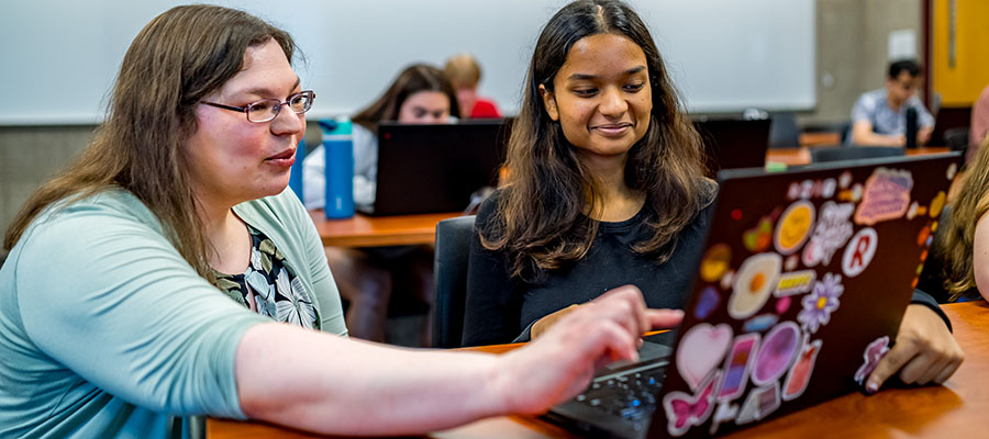 Student working with professor on a laptop.