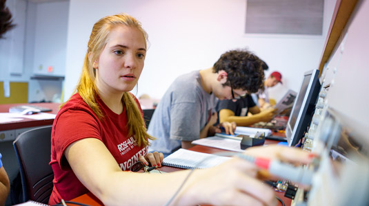 Students interact with professor in electrical engineering lab.