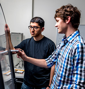 wo students inspecting a mechanical device in a lab