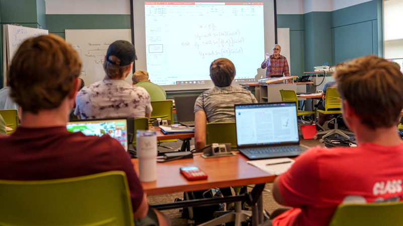 Professor Ditteon works with student in physics lab.