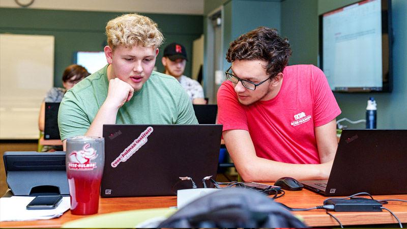 Two male students work together in classroom.