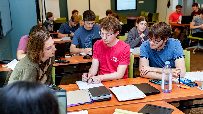 Female student uses scale in physics lab.