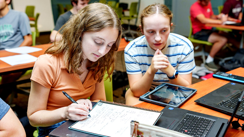 Two male students work together in classroom.