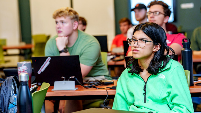 Male student works on laptop in classroom.