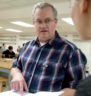 Dr. Duree talks to a student in a classroom.