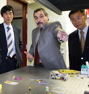 Dr. Granieri points toward device in laboratory as two men look on.