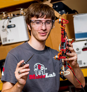 Male student holds part of a drone in one hand.