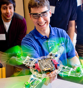 Male student holds running drone in one hand.