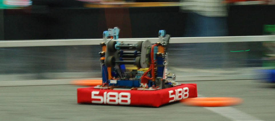 A robot zooms acrosss a competition field.