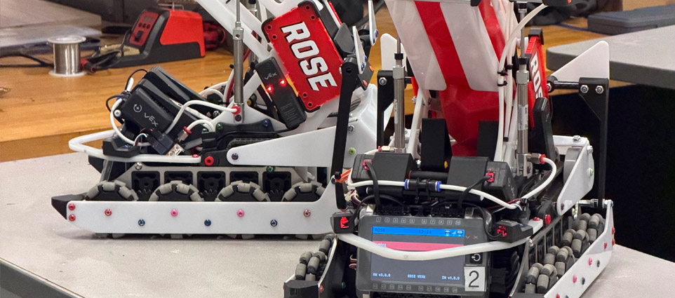 Three students work on a robot on a table in the BIC.