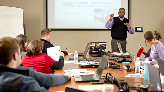 Dr. Craig Downing speaks to students seated around a large conference table.