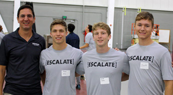 Three female students talking and smiling while wearing ESCALATE t-shirts.