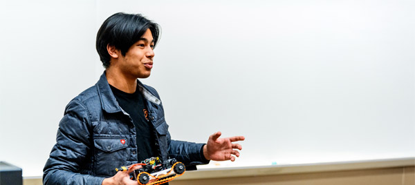 A student holding their design project makes a pitch during an entrepreneurship event.