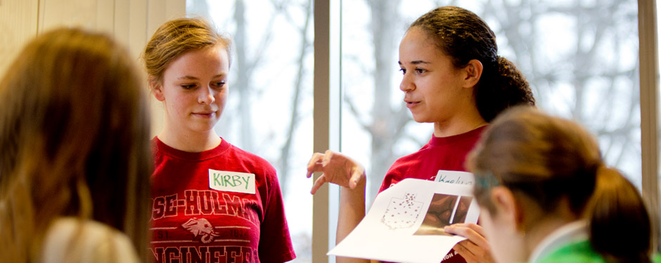 !Female student explains Grand Challenges activity. 