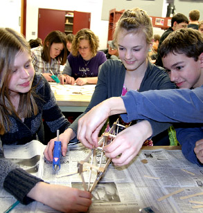 Young students glue together a small structure during Explore Engineering. 