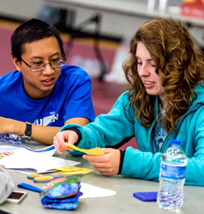 Two students work on hands-on project with paper and scissors.