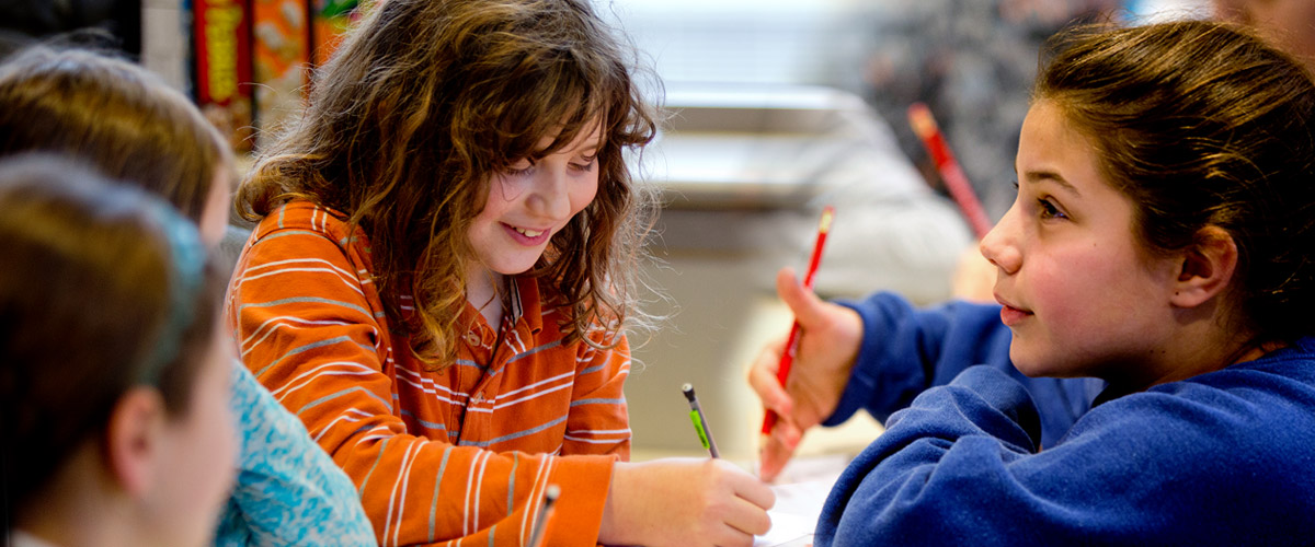 Smiling young students holding pencils and working during Explore Engineering program.