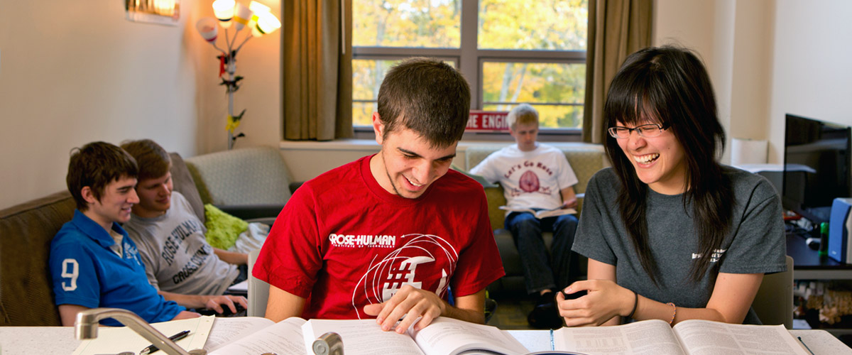 A male and female student smiling and reading a book, preparing for a study abroad experience.