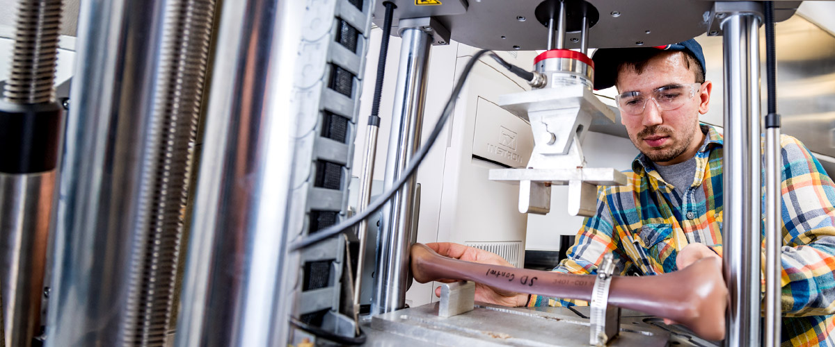 Male student working on an experiment with high tech equipment inside the Orthopaedic Biomedical Engineering lab.