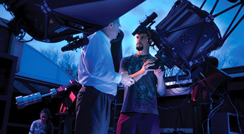 Large telescope in the foreground pointing at blue sky with other telescopes in background.