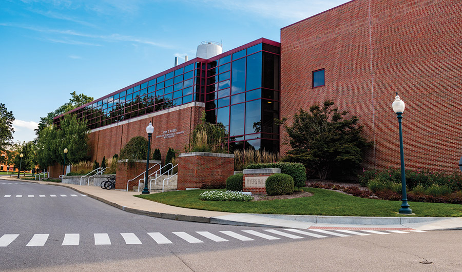 Blue sky reflecting off the glass windows making up the front of Myers Hall.