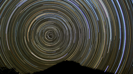 Time lapsed image of the southern hemisphere’s night sky showing the circular rotation of celestial bodies in a colorful star trail.