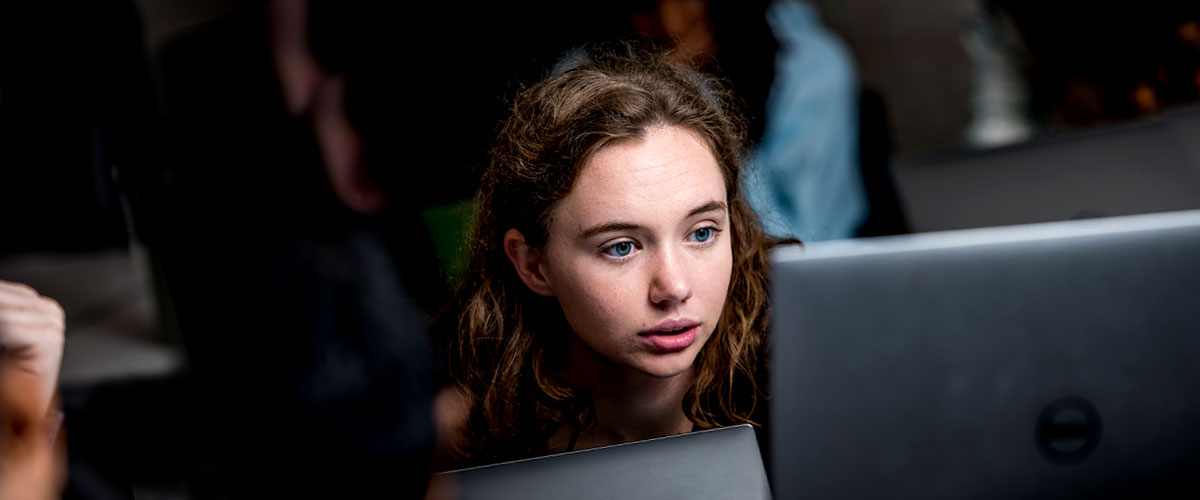 Female student reading class notes on a computer screen.