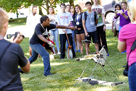 A  group of Catapult students working together on a project involving pieces of wood.