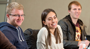 2 males and 1 female student sitting together smiling