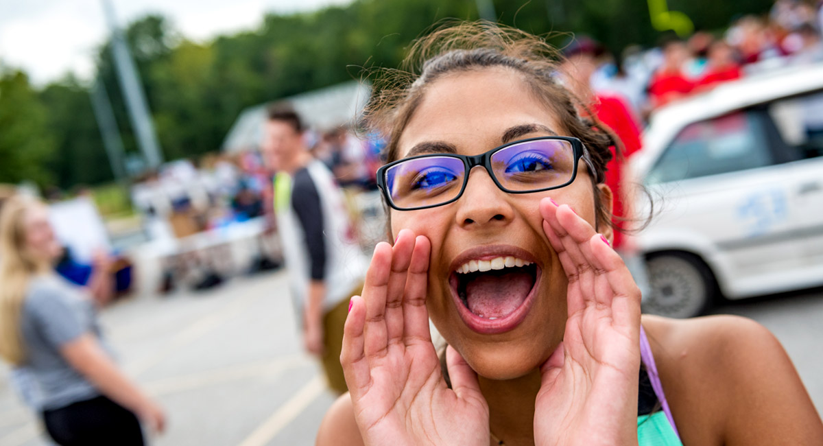 Female student smiling and shouting near Cook Stadium. 