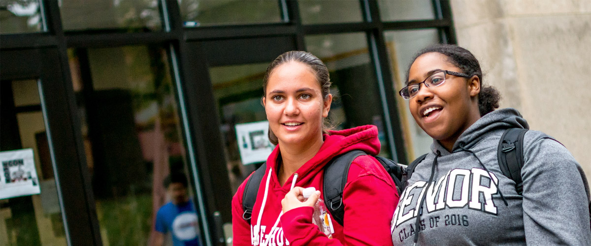 Two female students walking past Logan Library.