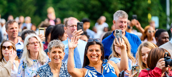 Parents cheer, wave, smile, and photos during the Commencement walk down the hill.