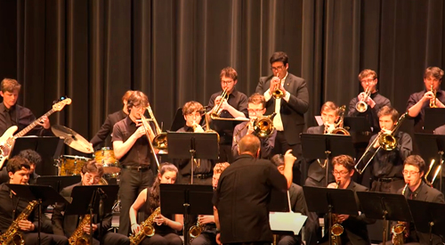 !Students performing on musical instruments on stage