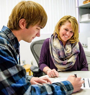 Male student filling out forms with a financial aid counselor.