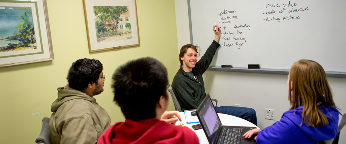 A small group of students working together using a whiteboard in the learning center.