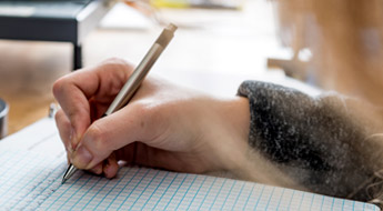 Close-up photo of student’s hand writing on graph paper.