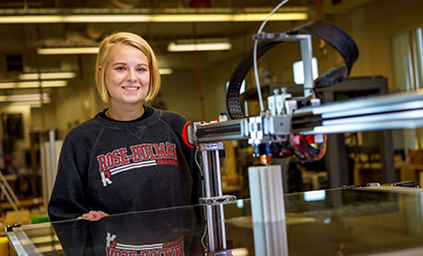 Student smiling at Ventures working with 3D printer.