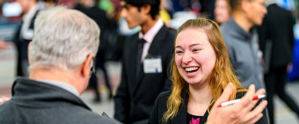 Student holds portfolio while talking to employer at Career Fair.