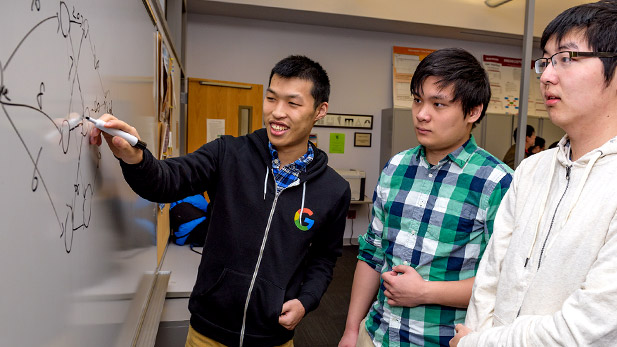 Three male students looking at a computer screen