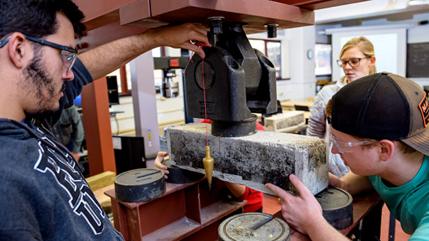 Students using equipment in a civil engineering lab to test the properties of concrete