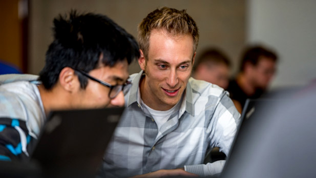 Sid Stamm looks at a laptop with a student